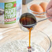 A person pouring Butternut Mountain Farm Very Dark Pure Vermont Maple Syrup into a bowl of eggs.