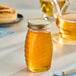A Classic Queenline glass honey jar with a gold metal lid on a table.