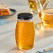 A Classic Queenline glass jar of honey on a table.
