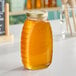 A Classic Queenline glass honey jar filled with honey on a table.
