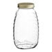 A clear glass Classic Queenline honey jar with a gold metal lid.