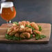 Breaded garlic cheese curds on a plate with a sprig of rosemary.