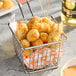 A metal basket filled with breaded garlic cheese curds on parchment paper.