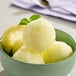 A bowl of lemon sorbet with a lemon slice on top.