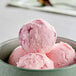 A bowl of pink and white swirled ice cream with a scoop on top.