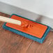 A 3M Doodlebug medium-duty blue scrub pad on a wooden surface.