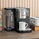A Keurig commercial single serve coffee maker with cups on a counter.
