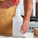 A hand holding a white plastic Lavex bottle of liquid.