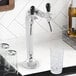 A Narvon undercounter water dispenser with a tap for chilled water and a glass of ice on a white counter.