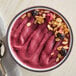 A bowl of organic acai sorbet topped with granola and dried berries.
