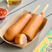 A Foster Farms jalapeno cheese chicken corn dog in a paper tray.