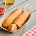 A tray of Foster Farms Honey Chicken Corn Dogs on a table in a stadium concession stand.