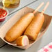 Two Foster Farms Honey Chicken Corn Dogs on a paper tray.