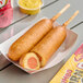 Two Foster Farms chili cheese chicken corn dogs in individual paper sleeves.