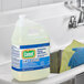 A gloved hand uses Comet cleaning bleach to clean a sink.