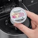 A hand holding a small white container of Bigelow Benefits Lemon and Echinacea Herbal Tea K-Cup Pods with a label.