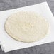A round white El Mejor tortilla on a white surface.