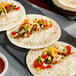 A group of El Mejor flour tortillas with meat and vegetables on them.