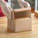 A person in gloves opening a Baker's Lane Kraft cake box.