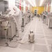 A man in a white suit using a Nilfisk stainless steel cleanroom canister vacuum.