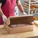 A person wearing gloves putting a cake in a Baker's Lane Kraft bakery box.
