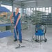 A man in blue overalls using a Nilfisk wet/dry vacuum to clean a floor.