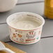 A white Painterland Sisters Savannah's Peach Organic Skyr Yogurt container with a spoon on a table.