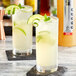 Two glasses of SHOTT Tahitian limeade with lime and mint garnish on a marble table.