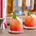 Two glasses of red SHOTT Pink Guava drinks garnished with mint and lime slices on a table.