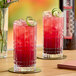 A close-up of two glasses of red SHOTT Blackcurrant and Lime energy drink with lime garnish.