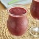 A glass of red smoothie made with Sambazon Organic Mixed Berries & Acai with a straw.