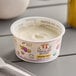A close-up of a Painterland Sisters Passion Fruit Organic Skyr Yogurt cup with a spoon inside.