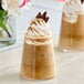 A glass of brown liquid flavored with SHOTT Cinnamon Syrup on a table with two cups of coffee.
