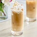Two glasses of iced coffee with whipped cream and almonds using SHOTT Caramelized Banana syrup.
