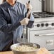 A person using a Tablecraft potato masher to mix food in a bowl.