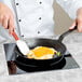 A chef using a Tablecraft countertop induction range to cook eggs in a pan.