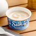 A container of Silk dairy-free vanilla almond milk yogurt alternative on a table.