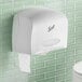 A white Scott Coreless Jumbo Roll toilet paper dispenser with a stub roll section on a green tile wall.