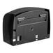 A black plastic Scott Coreless Jumbo Roll Toilet Tissue Dispenser with a hole in the middle.