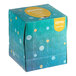 A Kleenex Naturals facial tissue cube with a blue and yellow plastic-free carton.