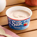 A container of Silk strawberry almond milk yogurt alternative with a spoon in it.
