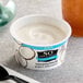 A close-up of a So Delicious Dairy-Free Plain Coconut Milk Yogurt cup with a spoon.