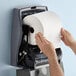 A hand holding a Scott Essential hard roll paper towel.