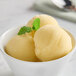 A bowl of Acai Roots Mango Pineapple cream sorbet with mint leaves.