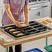A person in a purple shirt using a Sasa Demarle Flexipan® Origine silicone bread mold to put dough in a pan.