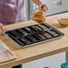 A woman pouring a brown liquid into a Sasa Demarle Flexipan scored bar mold.