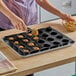 A person putting food into a Sasa Demarle mini muffin mold.
