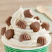 A cup of ice cream with chocolate peanut butter cups on top.
