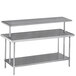 An Advance Tabco stainless steel middle mount shelf above a table with two shelves.