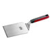 A stainless steel high heat solid beveled square edge turner with a red and black nylon handle.